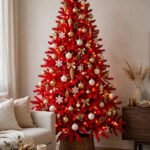 Red Christmas tree ideas: a festive tree with red and gold ornaments, red velvet ribbon, warm golden lights and a gold star topper in an elegant living room